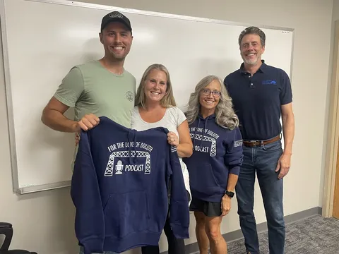 The Brix owners with the podcast hosts, holding a podcast sweatshirt after recording the episode