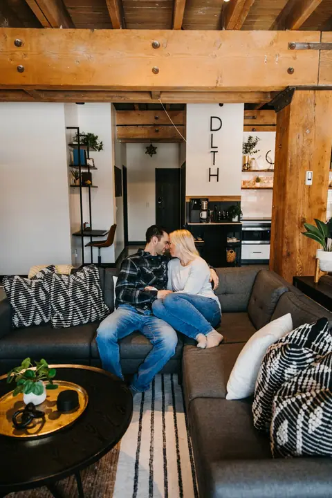 A couple relaxing on the sofa in a Brix condo with Douglas Fir beams in Canal Park