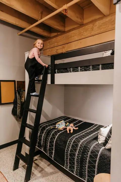 Child climbing the ladder to the top bunk in a Brix condo bunk room
