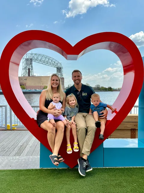The Brickson family in the red heart sculpture on the Duluth waterfront with the Aerial Lift Bridge behind